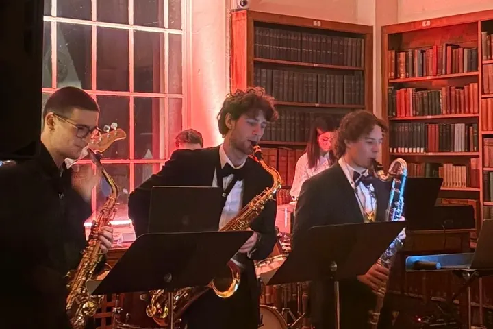 The horn section playing in a library, lit red