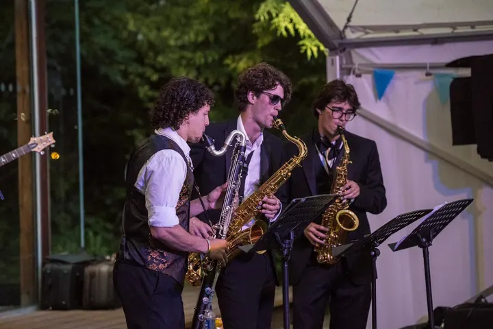 The horn section in waistcoats at a garden party