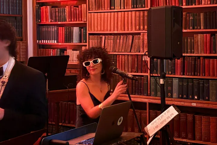 Keys player in white sunglasses between the bookshelves