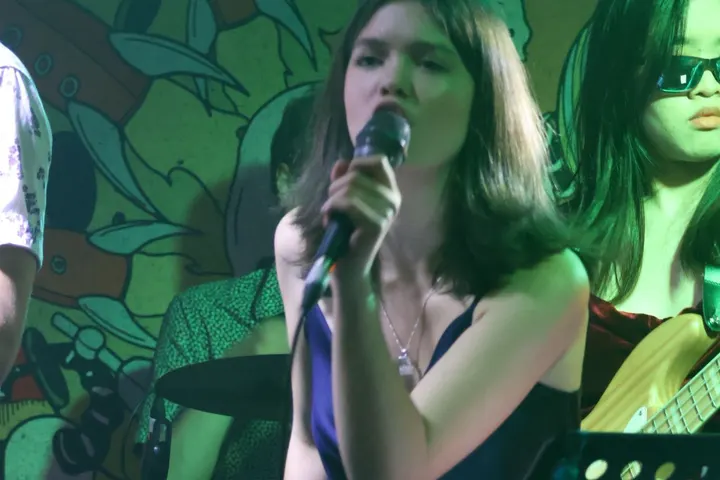 Singing in front of a painted wall, drums behind